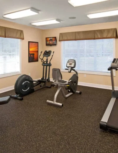 A bright community fitness center equipped with a treadmill, elliptical, stationary bike, and a multi-station weight machine